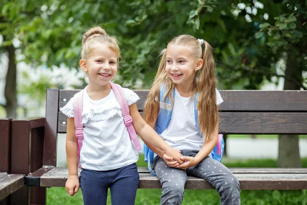 两个小孩笑着在长椅上聊天 这个概念又回到了学校 友谊和童年 — 图库照片