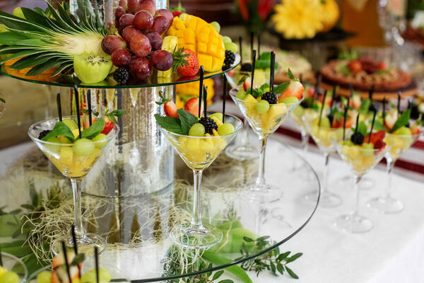 Fruit mix with pineapple, strawberries and blackberries and mint on the festive table. Delicious grapes. The concept of food, catering, restaurant and party celebration.