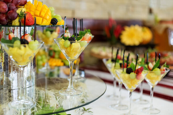 Fruit mix with pineapple, strawberries and blackberries and mint on the festive table. Delicious grapes and mangoes. The concept of food, catering, restaurant and party celebration.