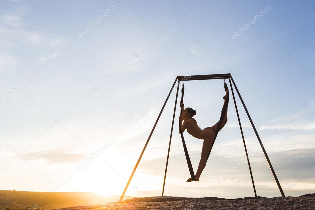 Girl practicing fly-yoga poses outdoor