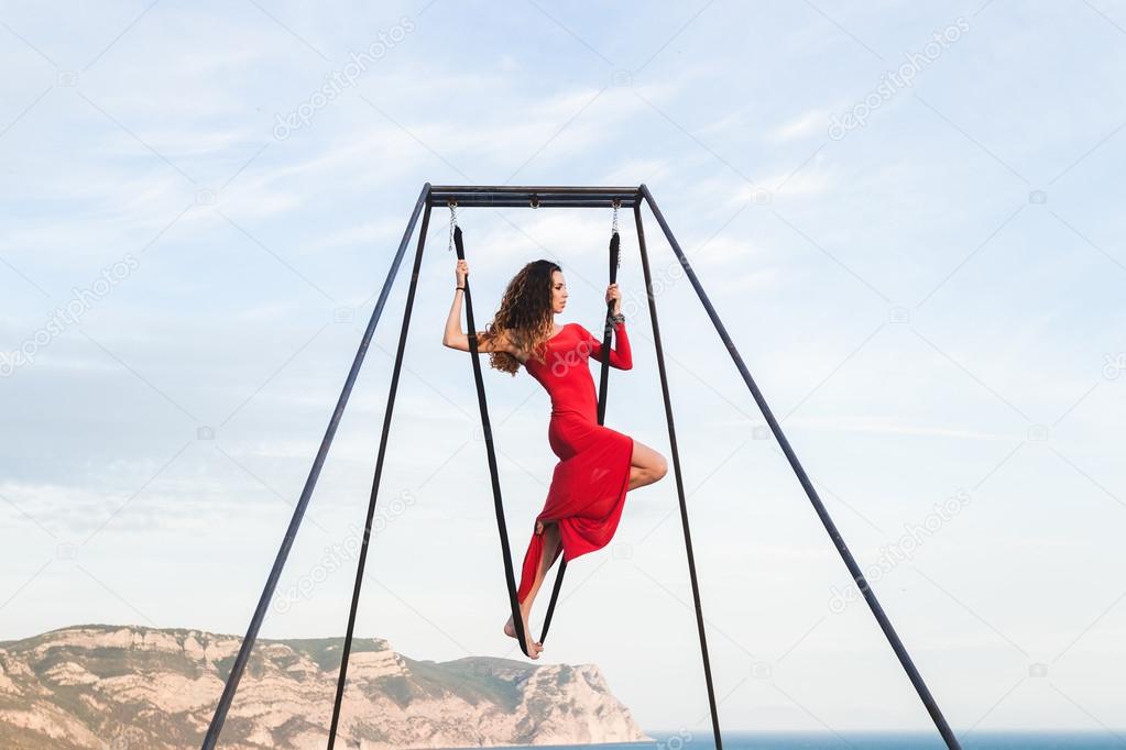Woman in red dress practicing fly-dance yoga