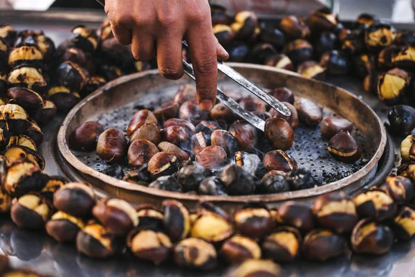 Homme préparant des châtaignes grillées — Photo