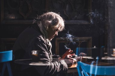 Gri saçlı adam kahve içer