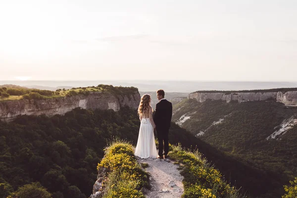 Pareja de boda caminando por el borde de la montaña — Foto de Stock