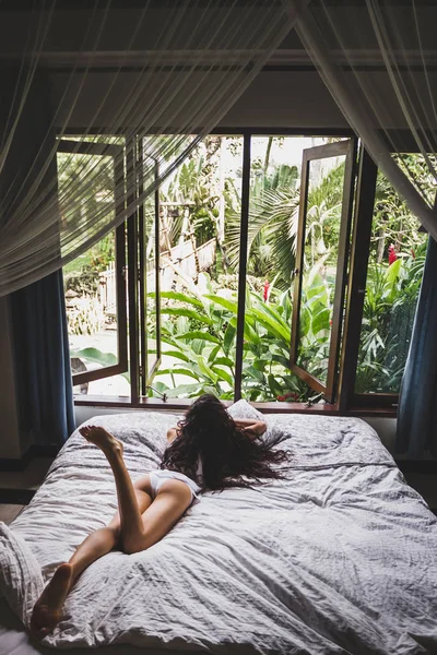 Žena v bílém prádle lenošení v posteli — Stock fotografie