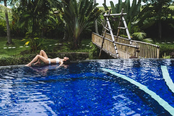 Γυναίκα χαλαρώνοντας στην πισίνα σε τροπικό Μπαλί — Φωτογραφία Αρχείου