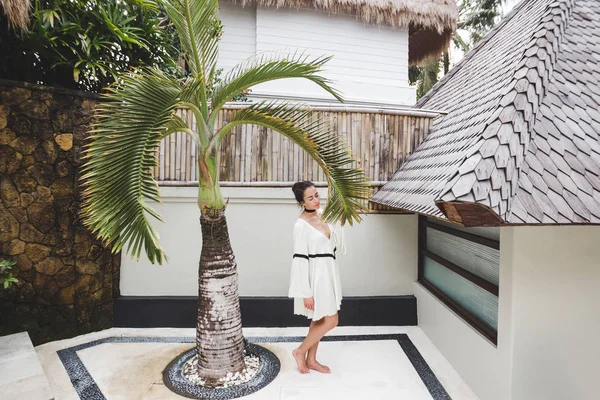 Woman in white tunic in tropical garden