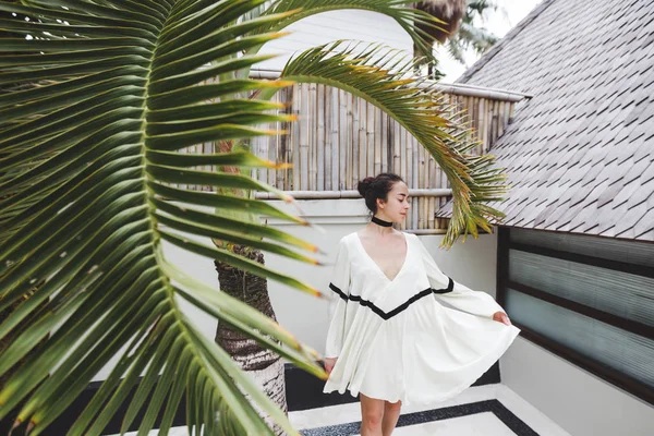 Woman in white tunic in tropical garden