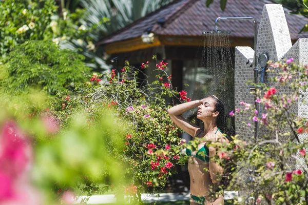 Woman taking shower in tropical garden — Stockfoto