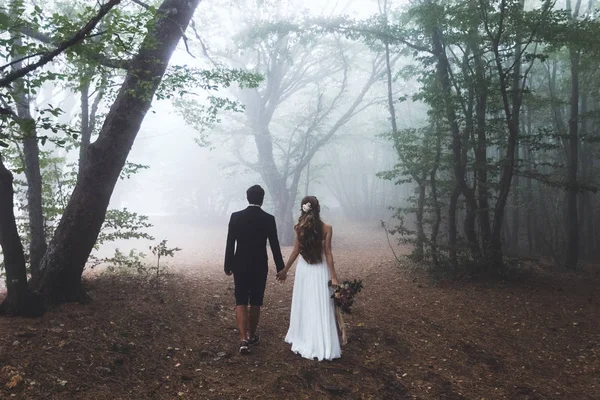 Bride and groom walking in forest — Stock Photo, Image