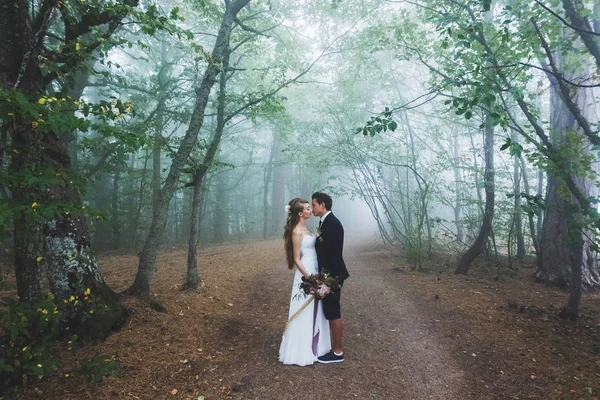 Bride and groom kissing in forest — Zdjęcie stockowe