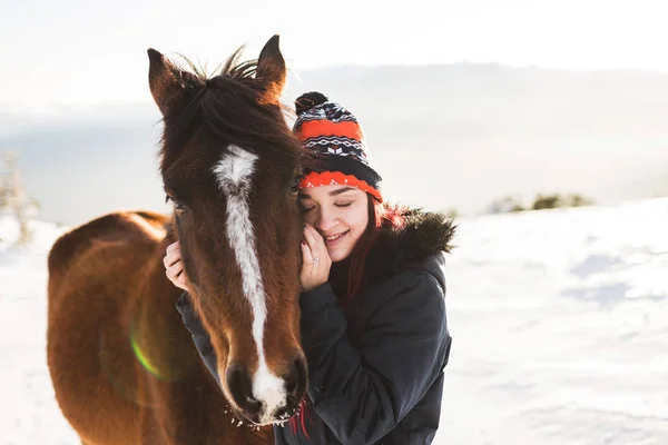 Gelukkig meisje zachtjes strelen paard in glanzende zonlicht — Stockfoto