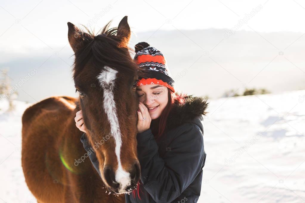 Happy girl gently stroking horse in shiny sunlight