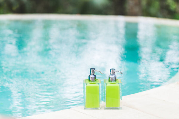 Флаконы шампуня на краю бассейна
