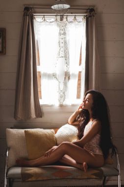 Beyaz ve bej yastık ile kanepede oturan kadın 