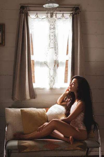 Beyaz ve bej yastık ile kanepede oturan kadın 