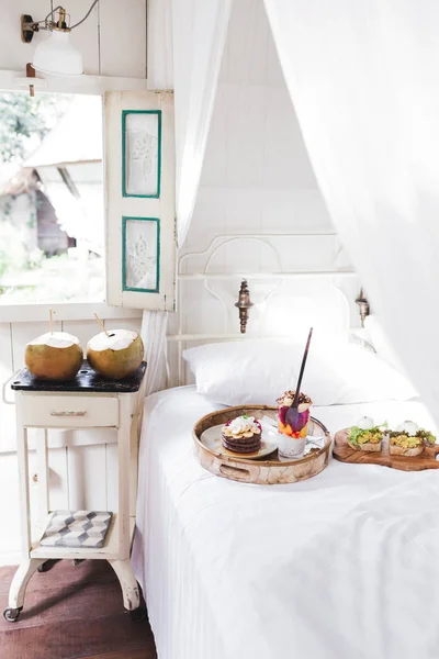 Fresh tasty breakfast in bed on wooden tray. — Stock Photo, Image