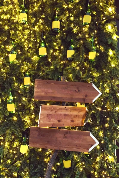 Три дерев'яні вказівники на фоні з ялиновими гілками в гірляндах — стокове фото