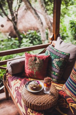 Dışarıda geleneksel Doğu süsler ile renkli yastıklar ile kanepede Servis Kahvaltı. Taze meyve muz, Hindistan cevizi ve chia pudingle ile Pancakes