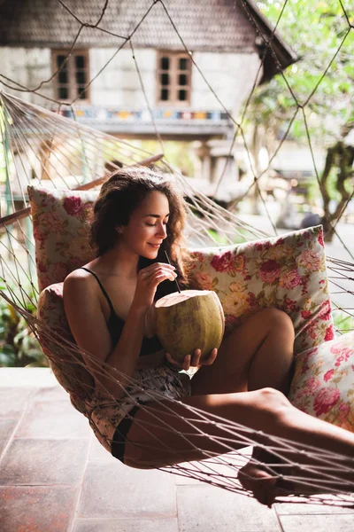Vrouw Zit Hangmat Met Kleurrijke Kussens Verse Jonge Kokosnoot Drinken — Stockfoto