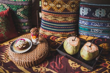 Dışarıda geleneksel Doğu süsler ile renkli yastıklar ile kanepede Servis Kahvaltı. Taze meyve muz, Hindistan cevizi ve chia pudingle ile Pancakes