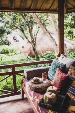 Dışarıda geleneksel Doğu süsler ile renkli yastıklar ile kanepede Servis Kahvaltı. Taze meyve muz, Hindistan cevizi ve chia pudingle ile Pancakes