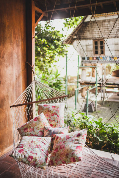 Hammock with colorful pillows hanging in hipster wooden house. P Stock Image