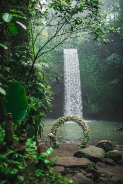 Wedding ceremony on Tibumana waterfall, Bali. Round arch with fr clipart