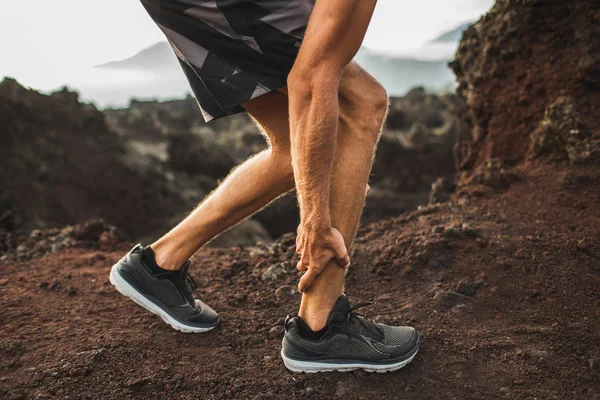 Male runner holding injured calf muscle and suffering with pain. — Stock Photo, Image