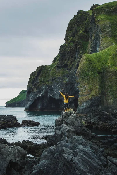 Woman walking by black stone rocky volcanic coastline of Vestman — Stock Photo, Image