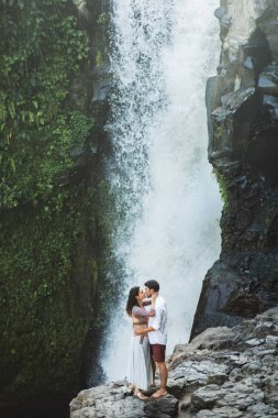Genç çift öpüşürken harika bir Tegenungan manzarası var.