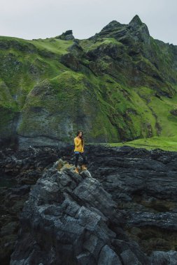 Vestman siyah taş kayalık volkanik kıyı şeridi ile yürüyen kadın