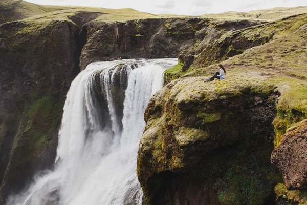 Donna seduta sul bordo con vista mozzafiato sull'acqua di Fagrifoss — Foto Stock