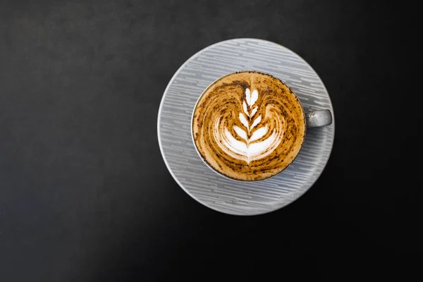 Gray cup of fresh cappuccino with chocolate on foam on dark blac — Stock Photo, Image