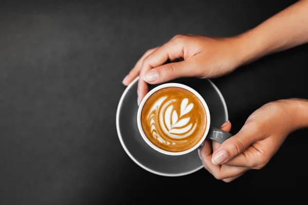 Egy csésze friss cappuccino női kézben sötét fekete fém asztalon — Stock Fotó