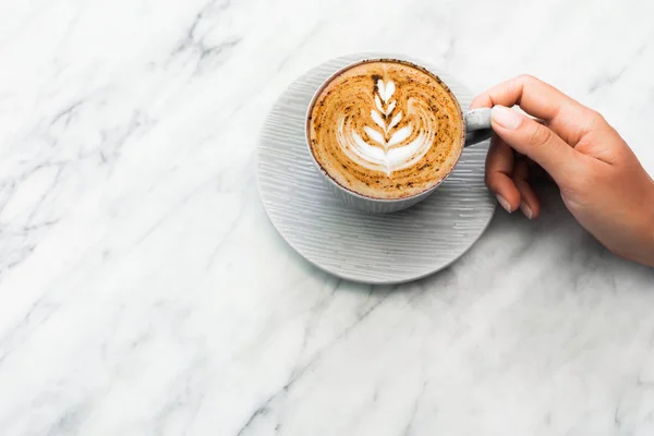 Copa de capuchino café fresco en las manos de la mujer en mármol blanco ta — Foto de Stock