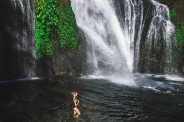 Kıvırcık saçlı, ince esmer kadın gölde eğleniyor. 