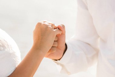 Damat, altın nişan yüzüğüyle gelinin elini nazikçe tutuyor. 