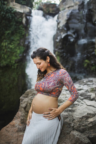 Young authentic pregnant woman near amazing cascade waterfall. N