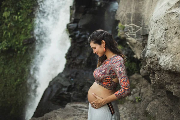 Jovem mulher grávida autêntica perto de cachoeira cascata incrível. N — Fotografia de Stock