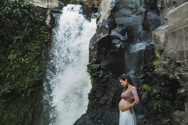 Jovem mulher grávida autêntica perto de cachoeira cascata incrível. N — Fotografia de Stock