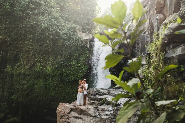 Jovem casal grávida apaixonado com vista incrível de Tegenungan c — Fotografia de Stock