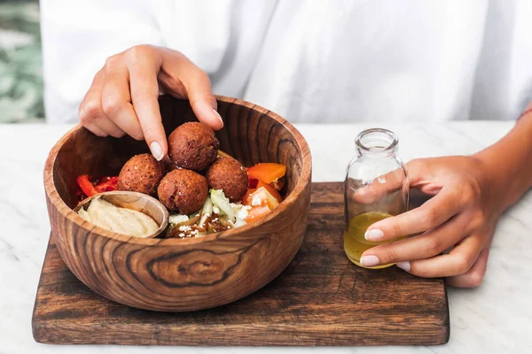 Wooden bowl with falafel balls, hummus and fresh salad. Woman ha — Stock Photo, Image