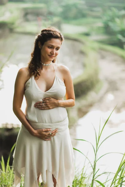 Bali pirinç tarlası manzaralı beyaz elbiseli genç hamile kadın. — Stok fotoğraf