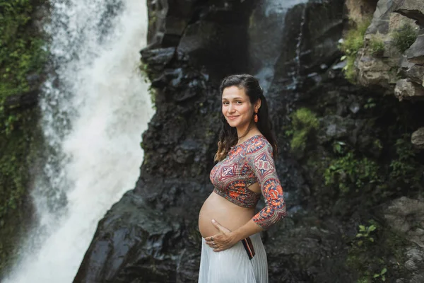 Jovem mulher grávida autêntica perto de cachoeira cascata incrível. N — Fotografia de Stock