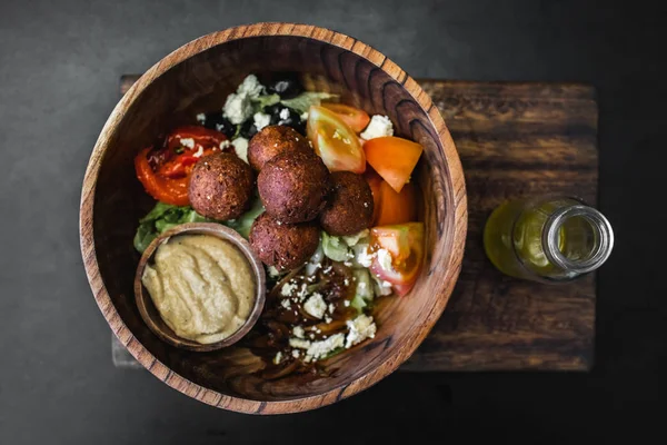Деревянная чаша с шариками фалафеля, хумус и свежий салат. Оливковое масло — стоковое фото