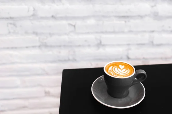 Egy szürke csésze friss cappuccino a fekete asztalon. A w háttere — Stock Fotó