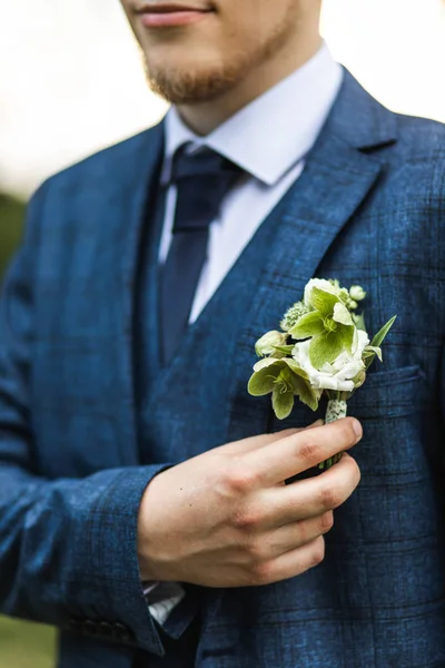 Noivo elegante em terno azul clássico segurando boutonni flor verde — Fotografia de Stock