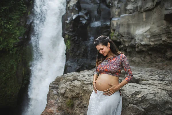 Jovem mulher grávida autêntica perto de cachoeira cascata incrível. N — Fotografia de Stock