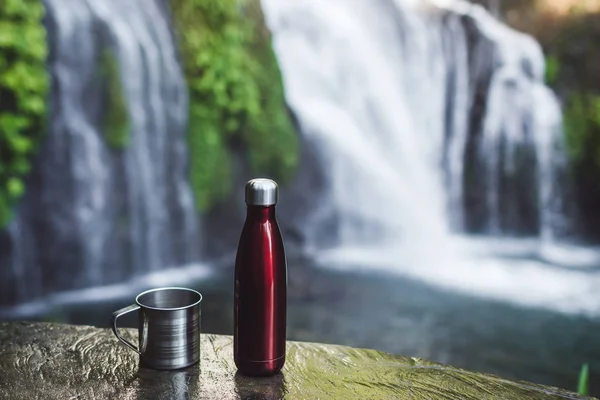 Rote Thermosflasche und Stahlbecher mit tropischem Hintergrund — Stockfoto